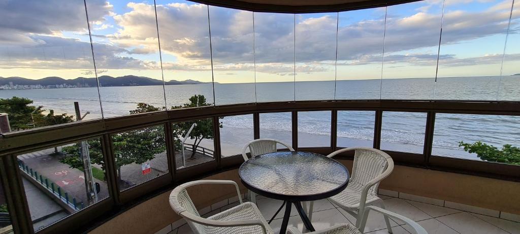 balcón con mesa, sillas y vistas al océano en Lindo Apto Itapema Meia Praia Frente ao Mar, 6 pessoas, alto padrão, en Itapema