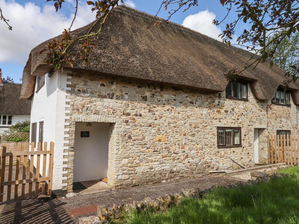 an old stone cottage with a thatched roof at Rose Cottage at Treaslake Farm in Honiton