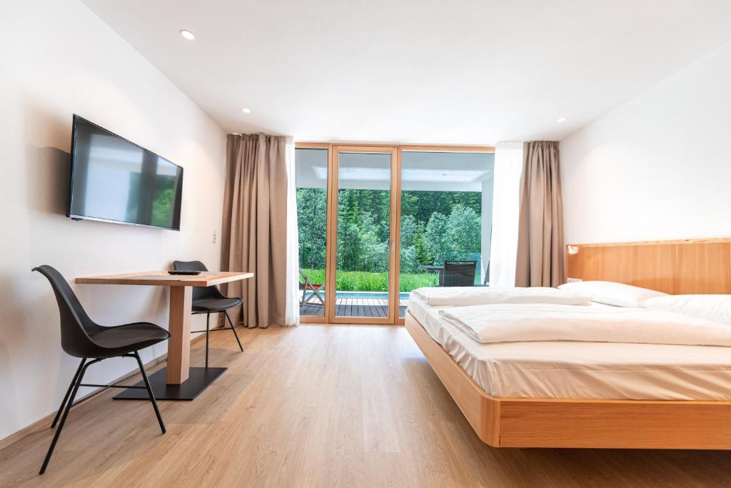um quarto com uma cama, uma secretária e uma televisão em Greva Apartments 2 em Santa Cristina in Val Gardena
