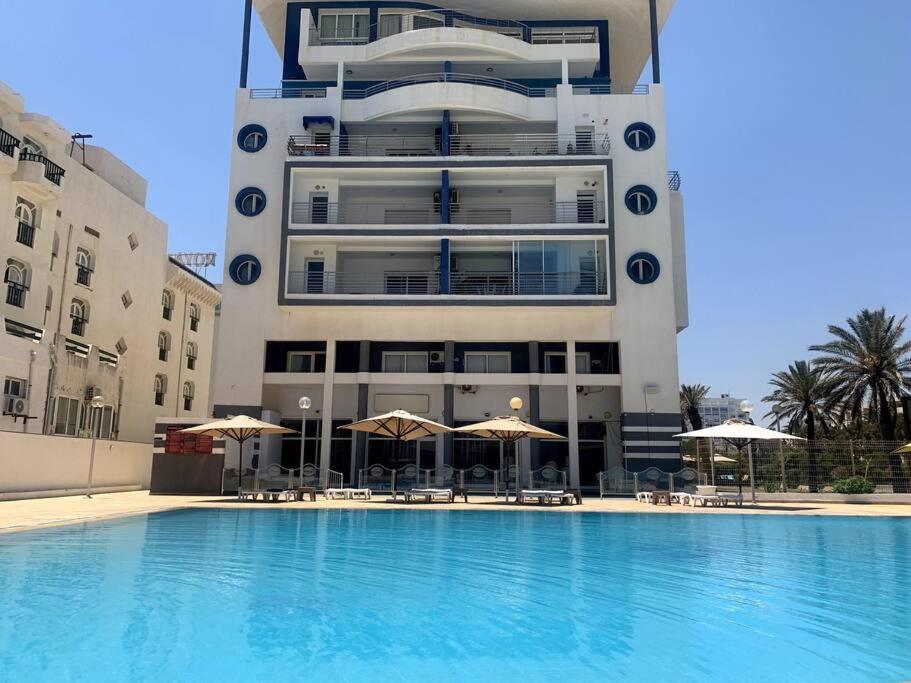 a building with a swimming pool in front of a building at Résidence Le Monaco Sousse in Sousse