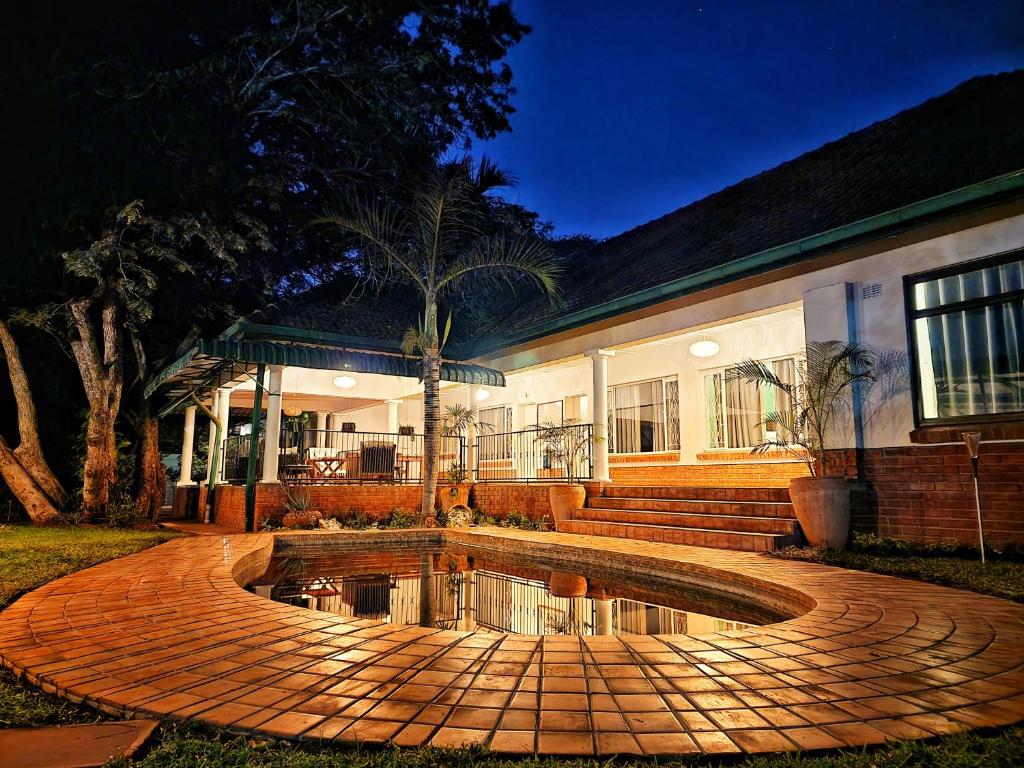 a house with a pond in front of it at Livingstone Lodge in Victoria Falls