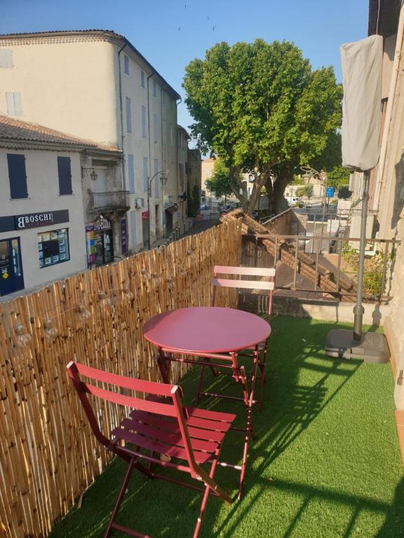 una mesa roja y sillas en un patio en Studio tout confort centre ville - Balcon, Clim, TV, Wifi, en Mazan