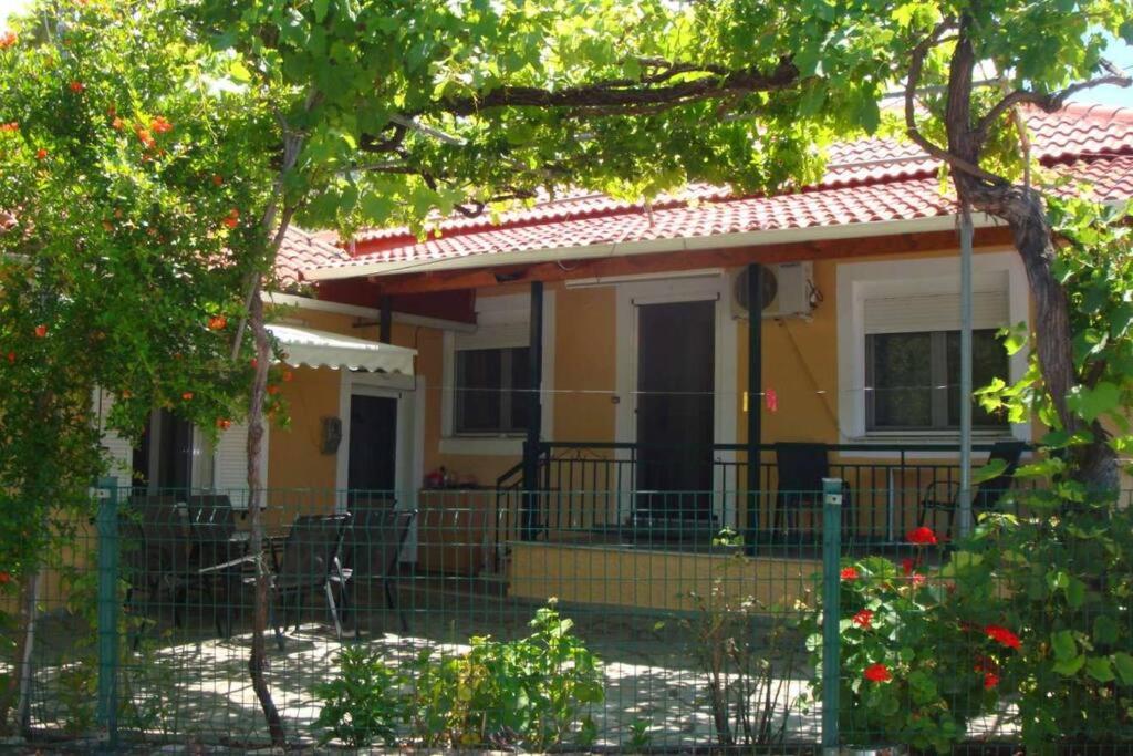 une maison jaune avec une clôture devant elle dans l'établissement Grapes and Roses, à Igoumenítsa