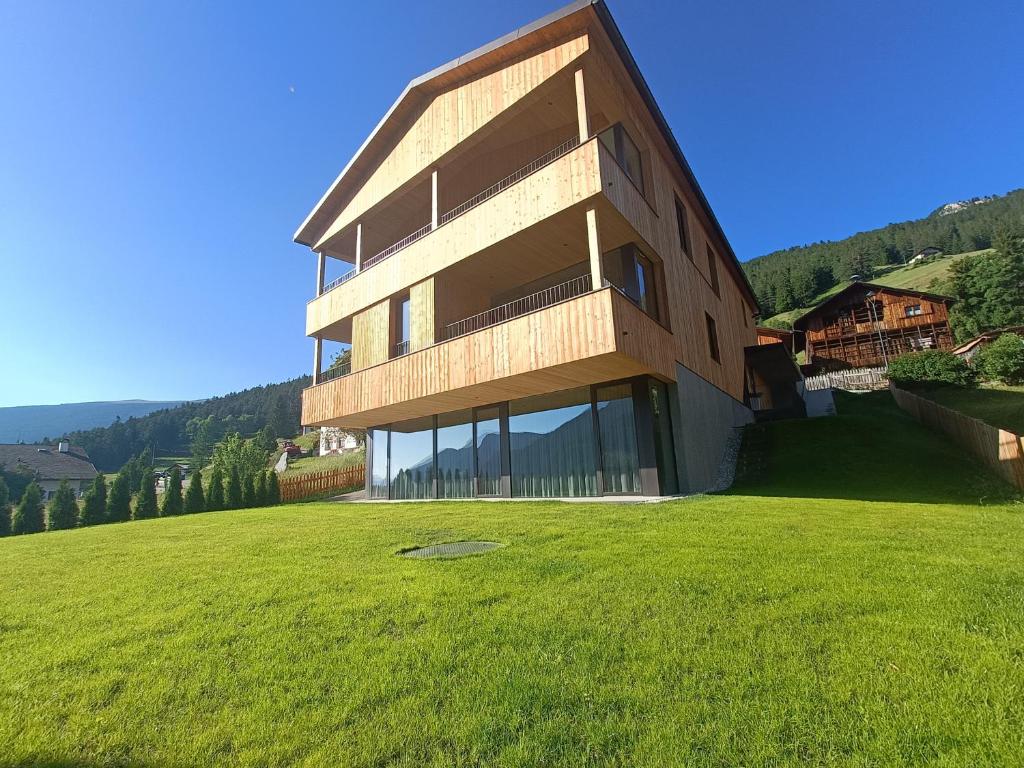 a building on a hill with a green field at Apartments Emilia in Ortisei