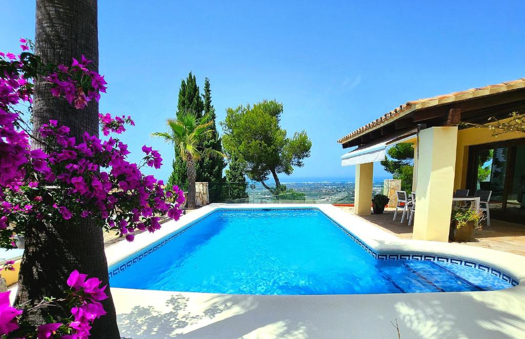 uma piscina em frente a uma casa com flores roxas em Exclusive Villa at La Sella Resort em Pedreguer