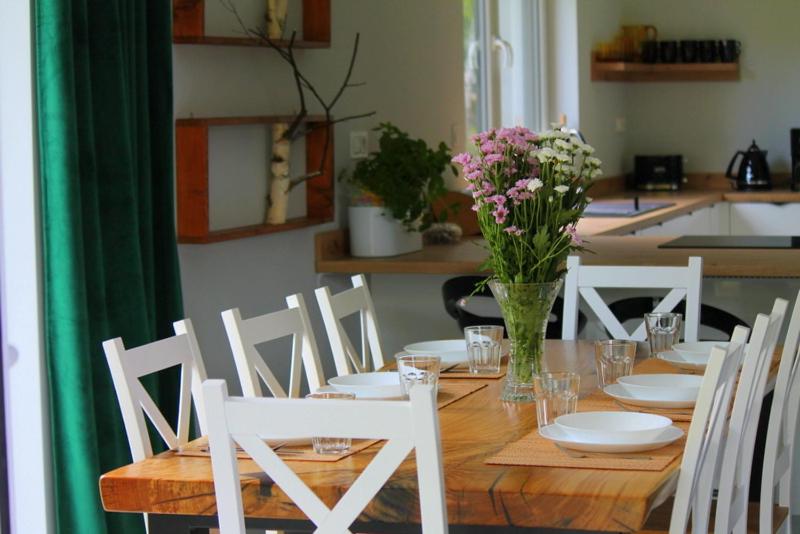 une table en bois avec des chaises blanches et un vase de fleurs dans l'établissement BetullaHouse, à Nakielno