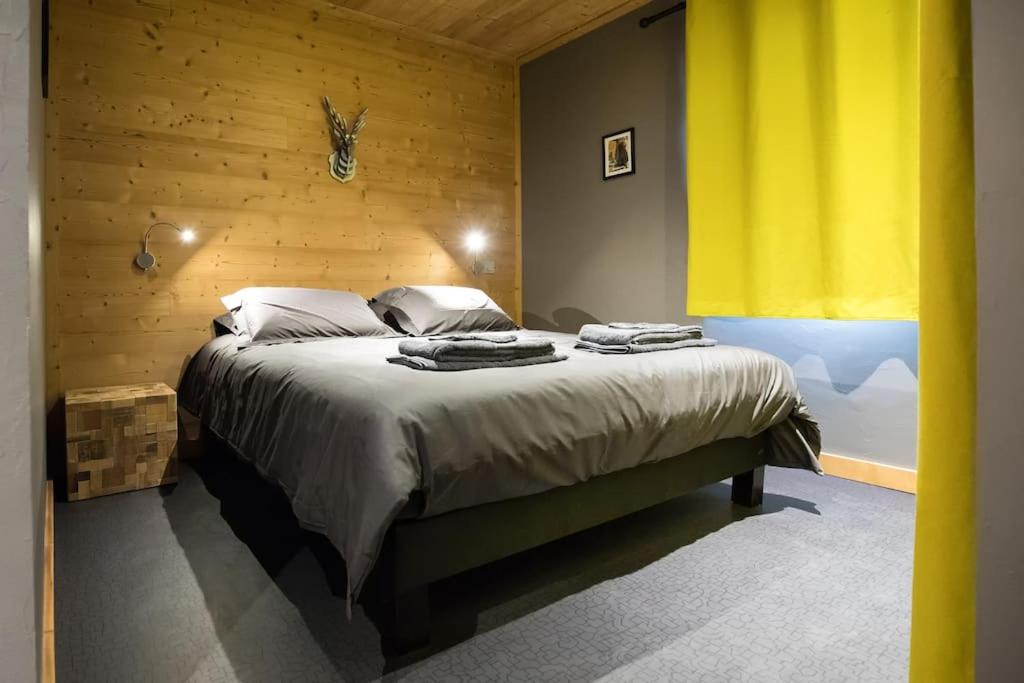 a bedroom with a large bed with a yellow curtain at HaKaJu Appartement 10 personnes à Val Cenis in Lanslebourg-Mont-Cenis