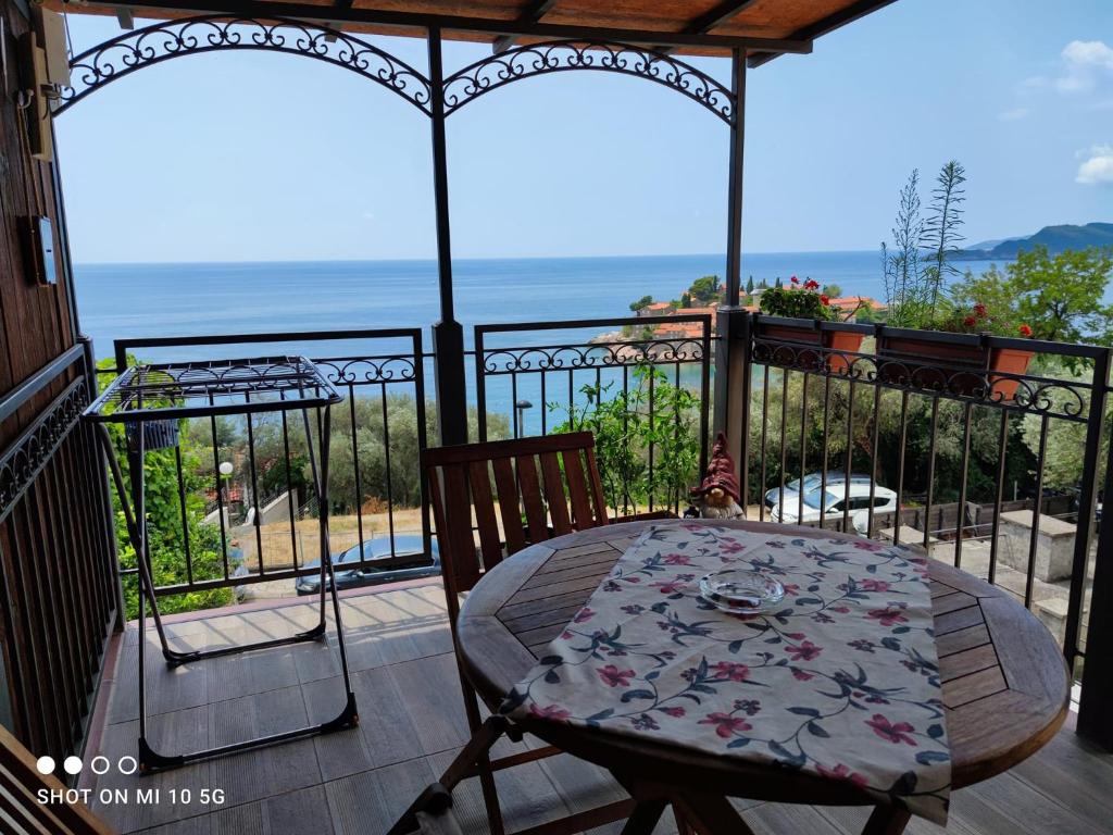 a table and chair on a balcony with the ocean at Apartmani Fortunela in Sveti Stefan