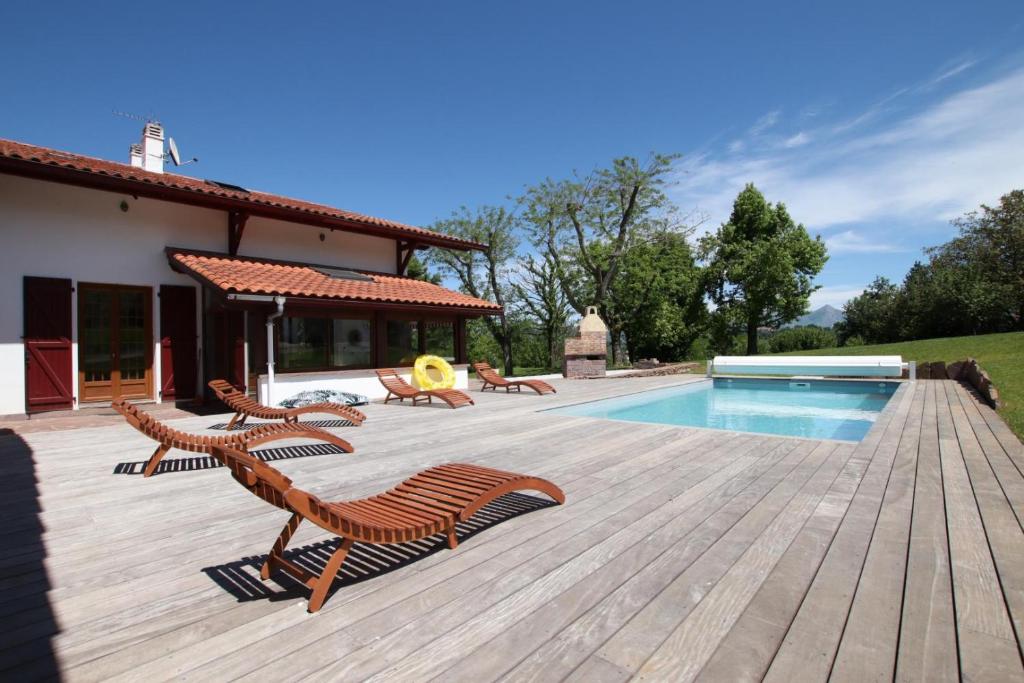 una terraza de madera con sillas y una piscina en Arlotia, en Ascarat