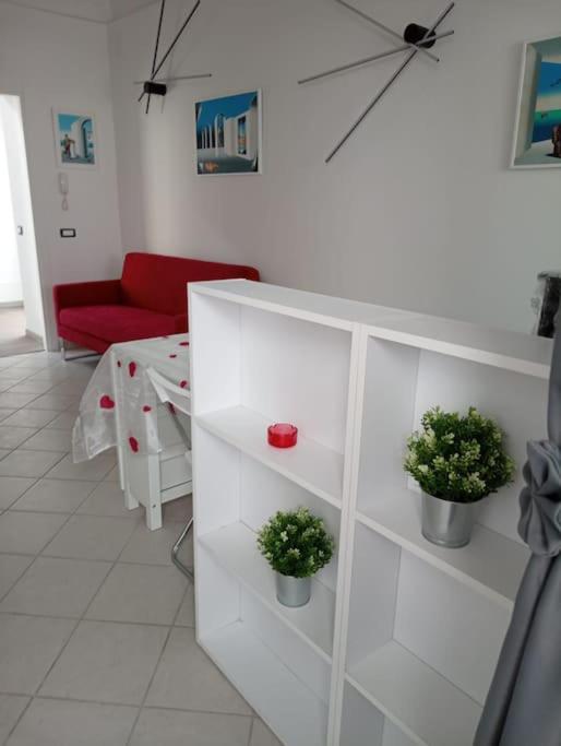 a white living room with a red couch and potted plants at Neruda Chic House Sant'Angelo in Sant'Angelo D'Ischia
