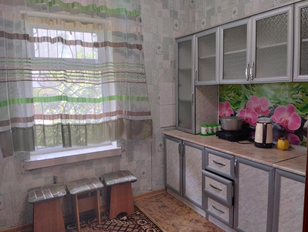 una cocina con armarios grises, una ventana y una encimera en Karakol apartment, en Karakol