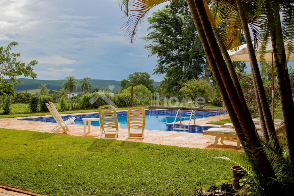 uma piscina com duas cadeiras e uma mesa ao lado em Casa em condomínio com piscina e acesso a represa em Itaí