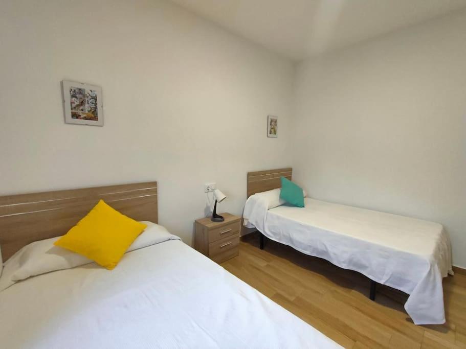 a bedroom with two beds and a yellow pillow at Apartamento Acerota, con parking gratuito in Córdoba