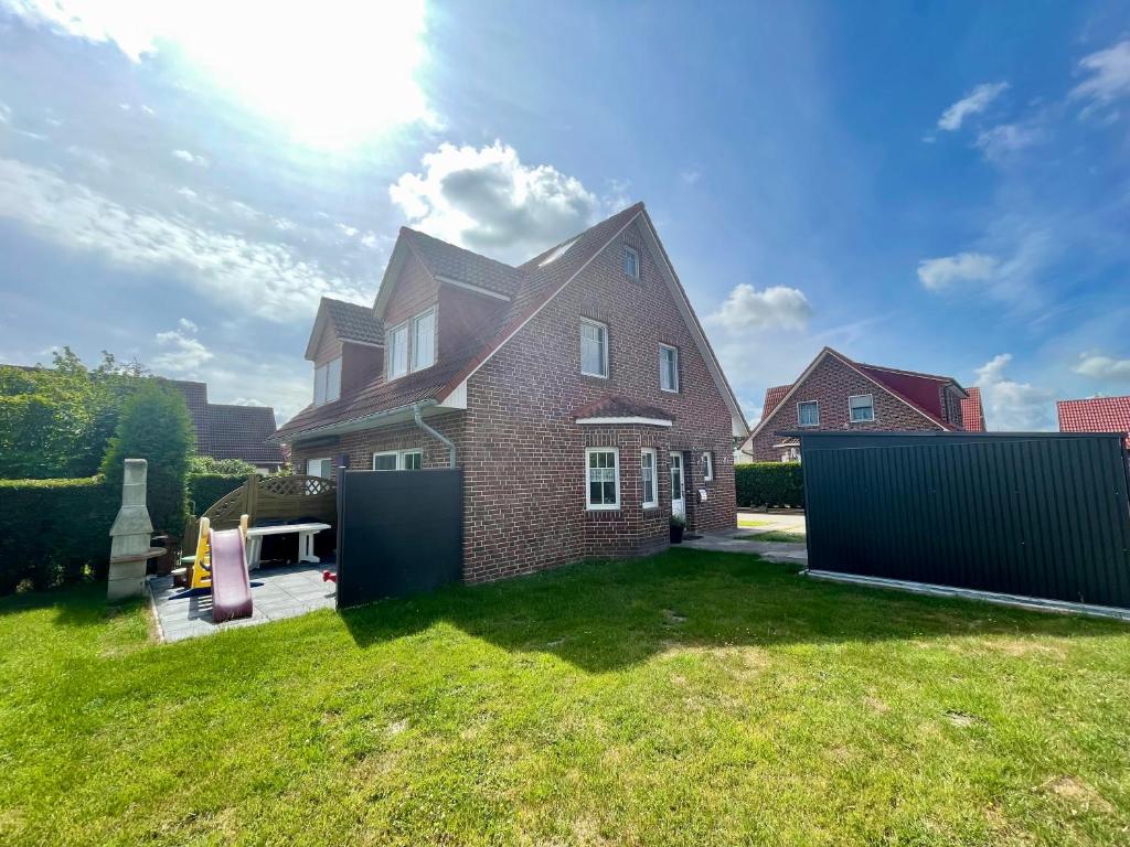 a brick house with a fence in a yard at Möwennest in Krummhörn
