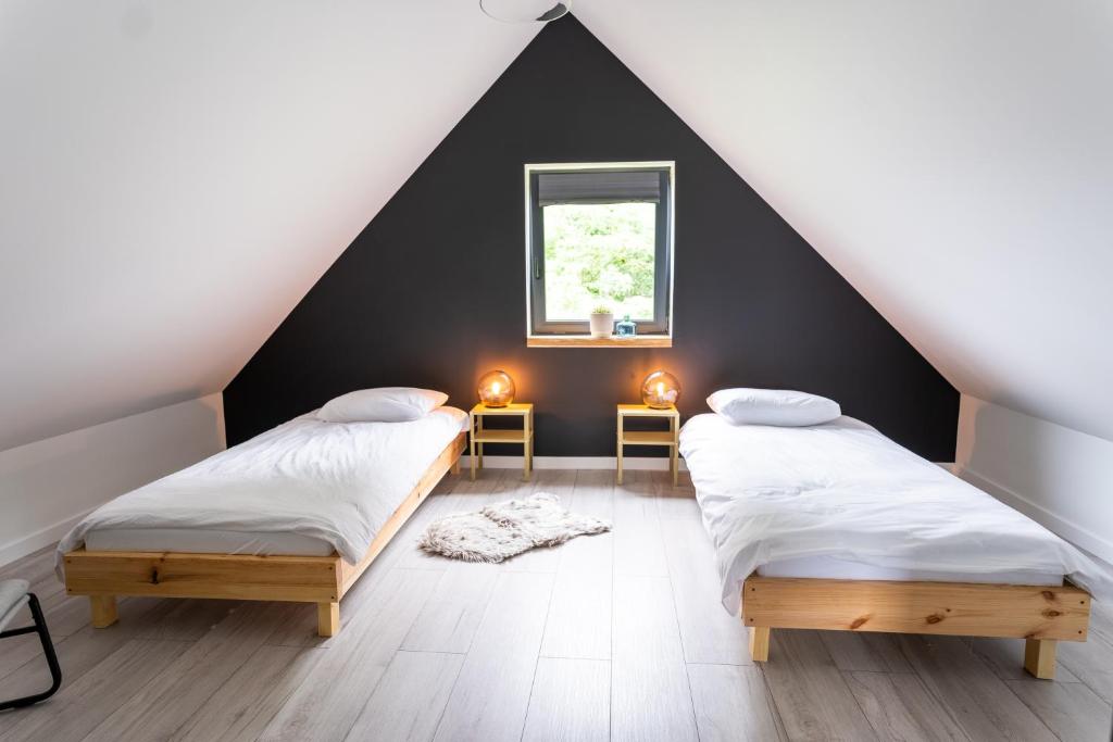 2 łóżka w sypialni na poddaszu z czarną ścianą w obiekcie Sosnowy Plan w mieście Józefów