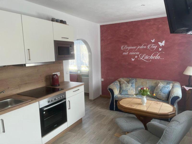 eine Küche und ein Wohnzimmer mit einem Tisch und einem Sofa in der Unterkunft Ferienhaus der Familie Demmler in Crottendorf