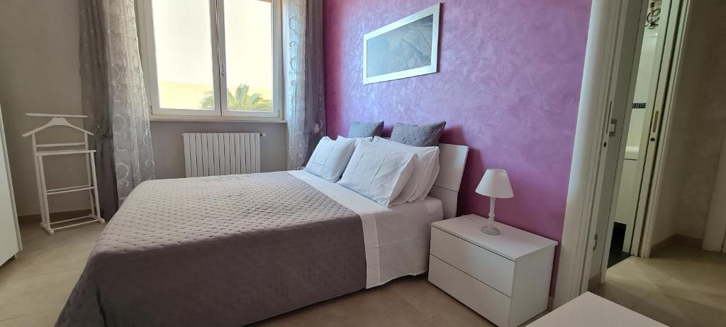 Un dormitorio con una cama y una pared morada. en Greenwich House, en Monopoli