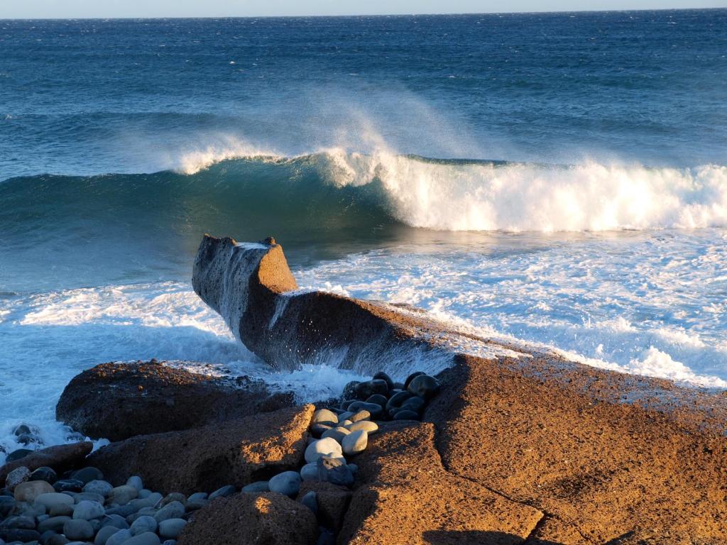 una ola chocando en la orilla de una playa en sunrise directly at the sea, en La Mareta