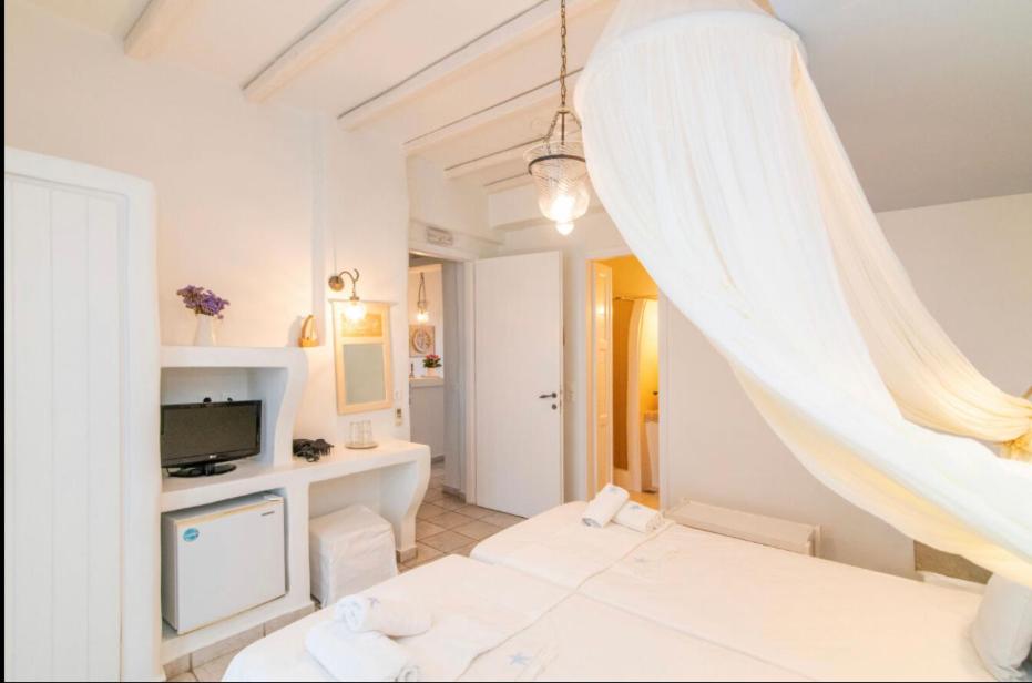 een witte kamer met een bed en een televisie bij Studios Eleni II in Tinos Town