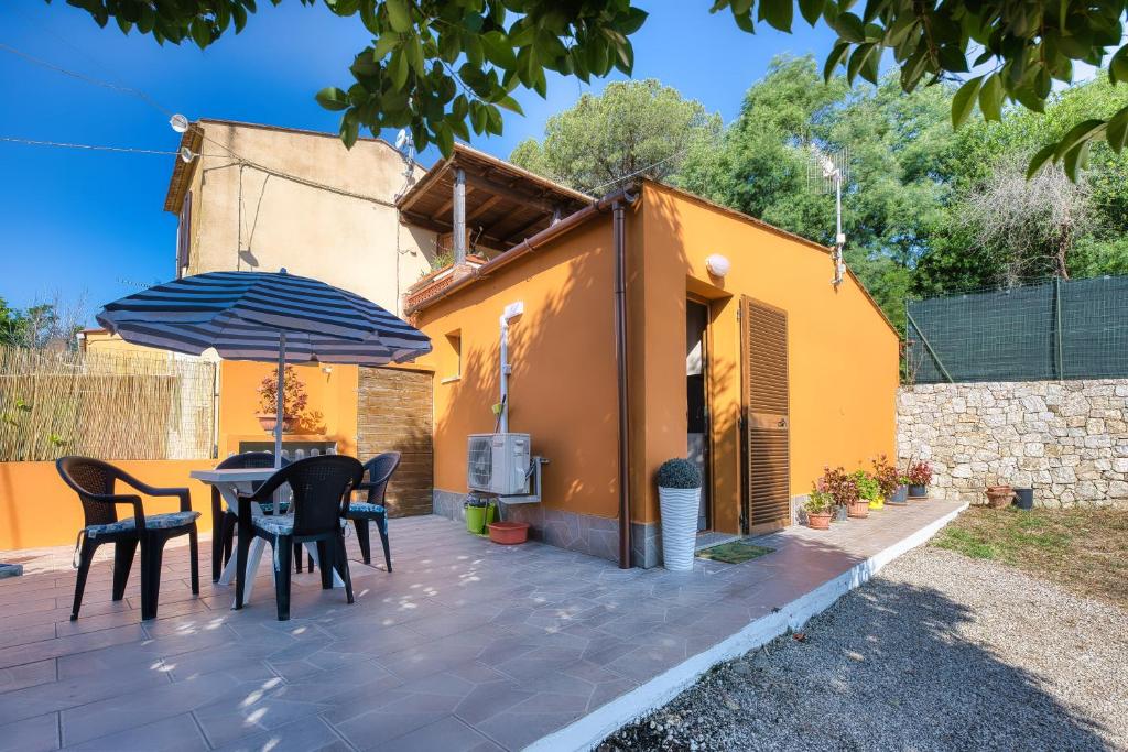 patio con tavolo, sedie e ombrellone di La Casina di Alan - Goelba a Porto Azzurro