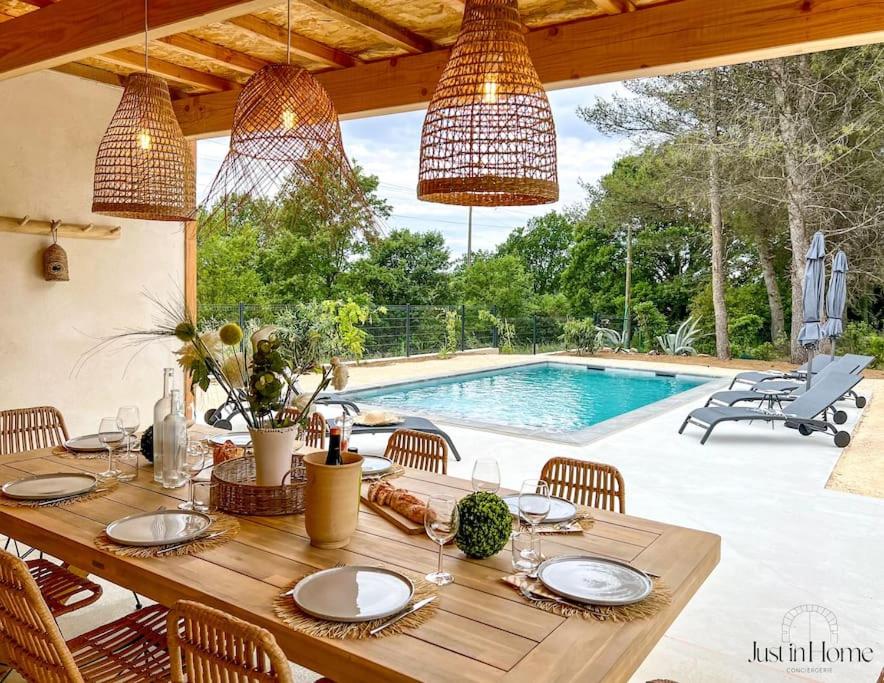 une table à manger avec des chaises et une piscine en arrière-plan dans l'établissement Villa standing Uzès,piscine,clim, à Uzès