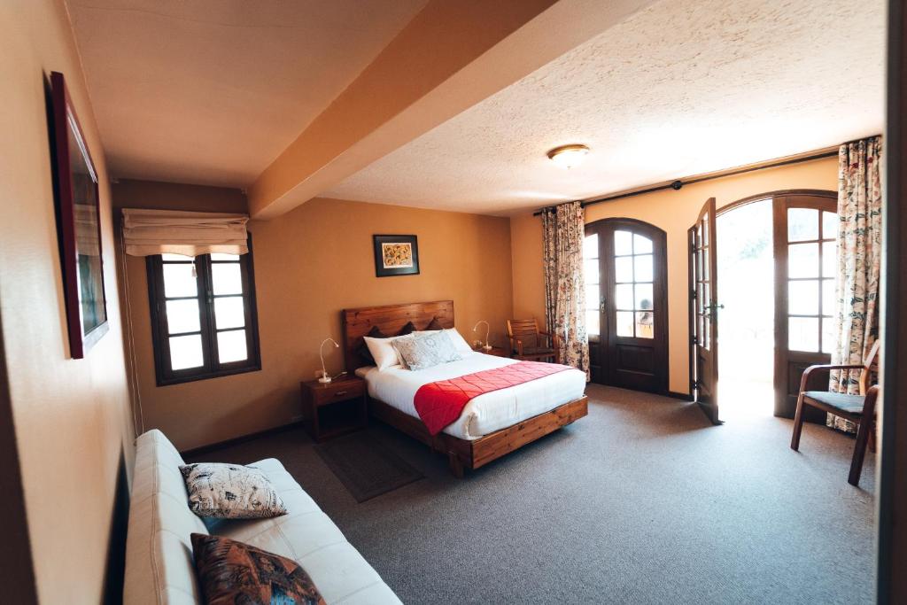 een slaapkamer met een bed en een bank bij Hotel Boutique La Casa de Margarita in Cochabamba