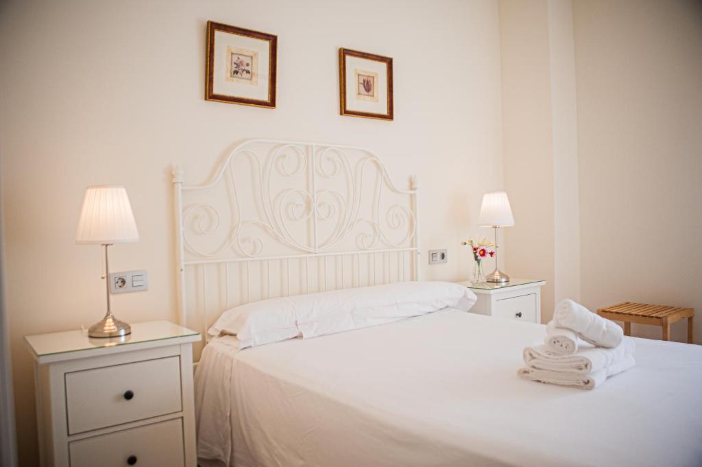 um quarto com uma cama branca e toalhas em Ramón y Cajal by TheGoodTourist em Sevilha