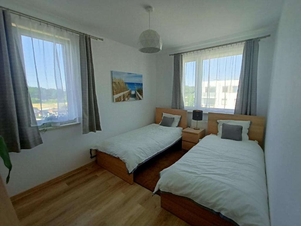 a bedroom with two beds and two windows at Apartament Stogi in Gdańsk