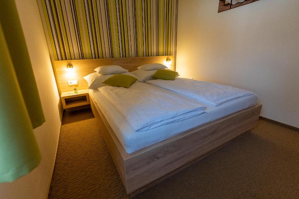 1 dormitorio con 1 cama blanca grande con almohadas verdes en Belvárosi Nemes Apartmanház Szekszárd, en Szekszárd
