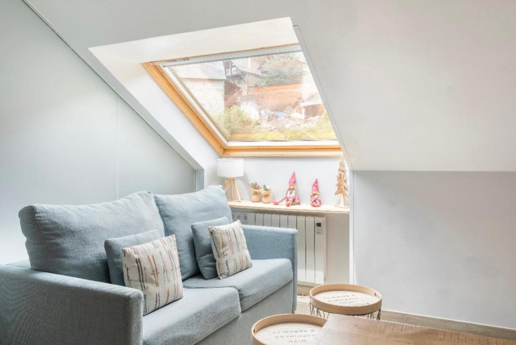 a living room with a blue couch and a skylight at CHIC HUMARALET, pie de pistas, free parking in Baqueira-Beret