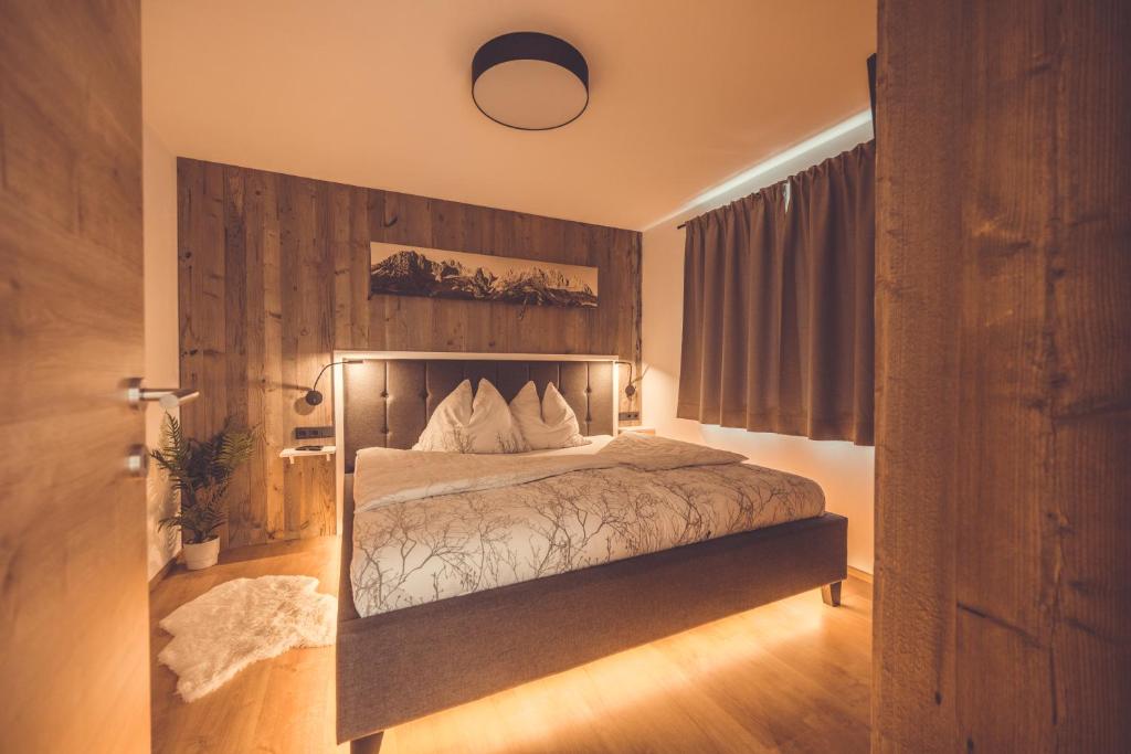 1 dormitorio con 1 cama con pared de madera en Apartment Gipfelblick, en Kirchdorf in Tirol