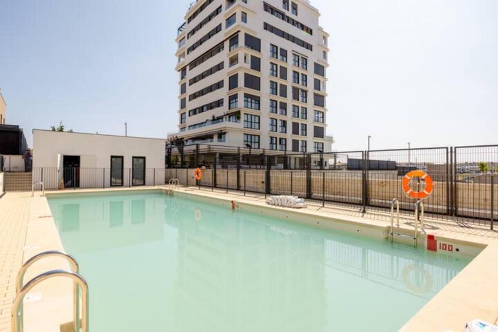 una gran piscina con un edificio alto en el fondo en Piso climatizado y parking, en Madrid