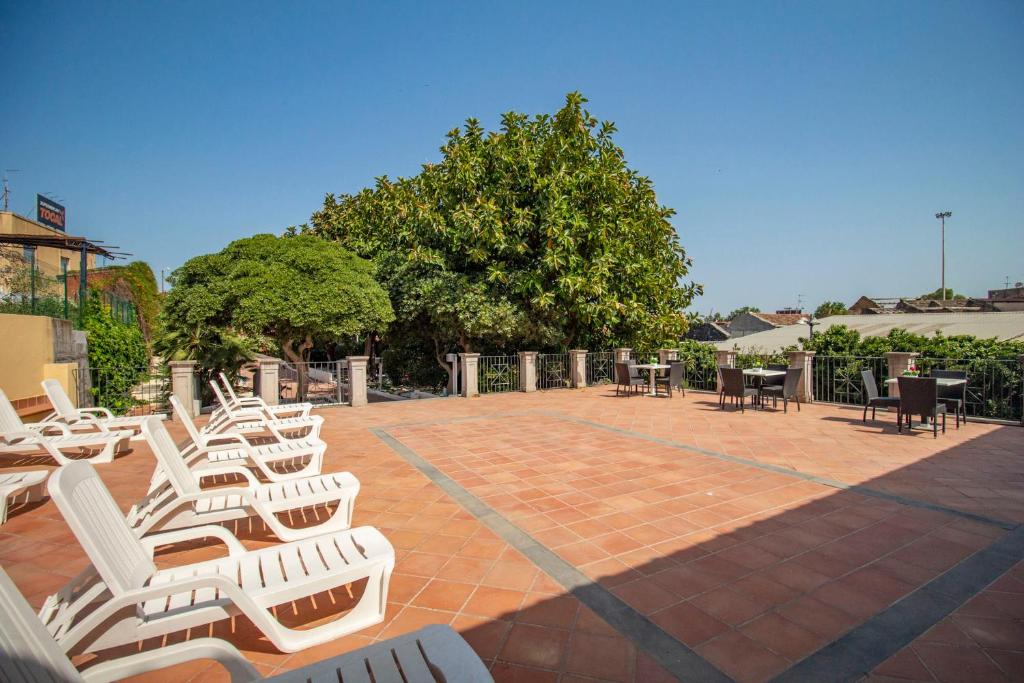 a group of white chairs and tables on a brick patio at Royal Playa Suite and Apartament -private parking- self chek out in Catania