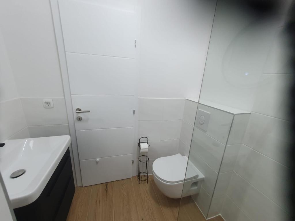 a white bathroom with a toilet and a sink at MB Apartman in Čapljina