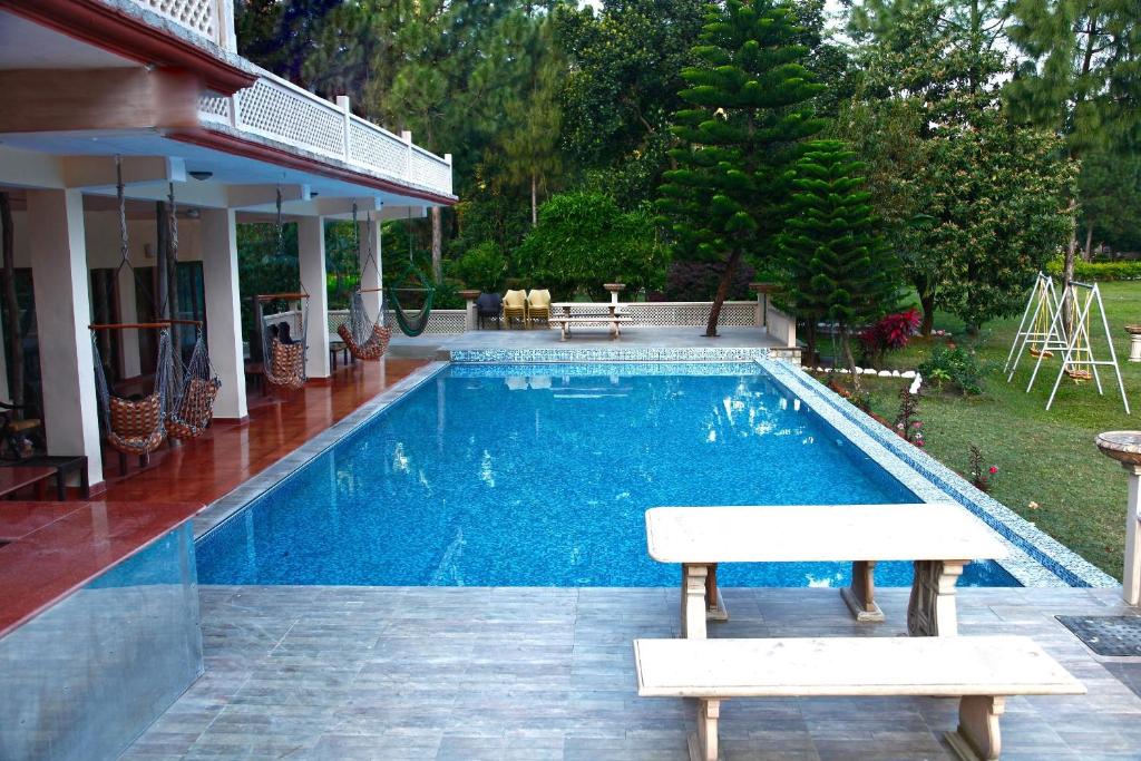 a swimming pool with a bench next to a house at Riverside By Aahma in Garjia