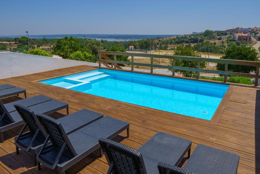 uma piscina no topo de um deque de madeira com cadeiras e uma mesa em Casa Dona Maria em Montargil