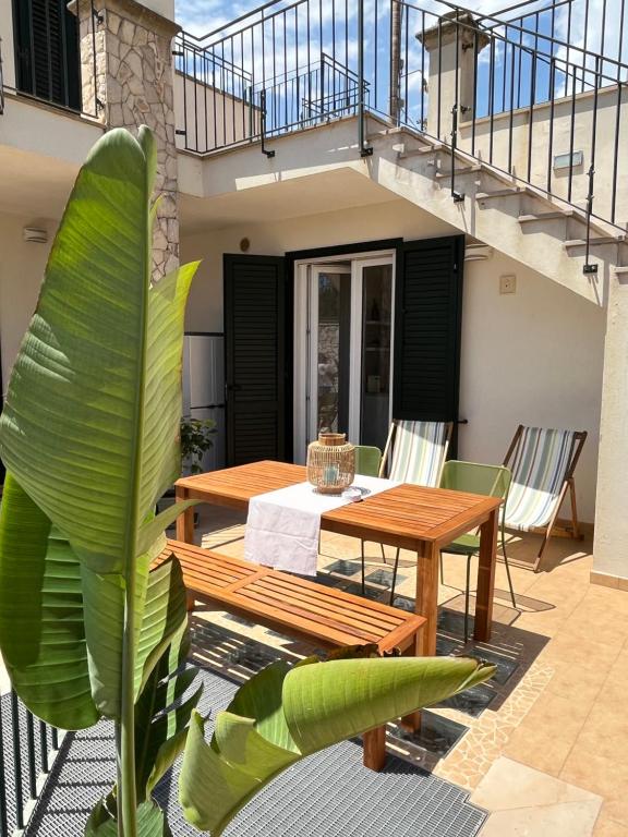 un patio con una mesa y sillas de madera y una escalera en Itaca, en Castro di Lecce