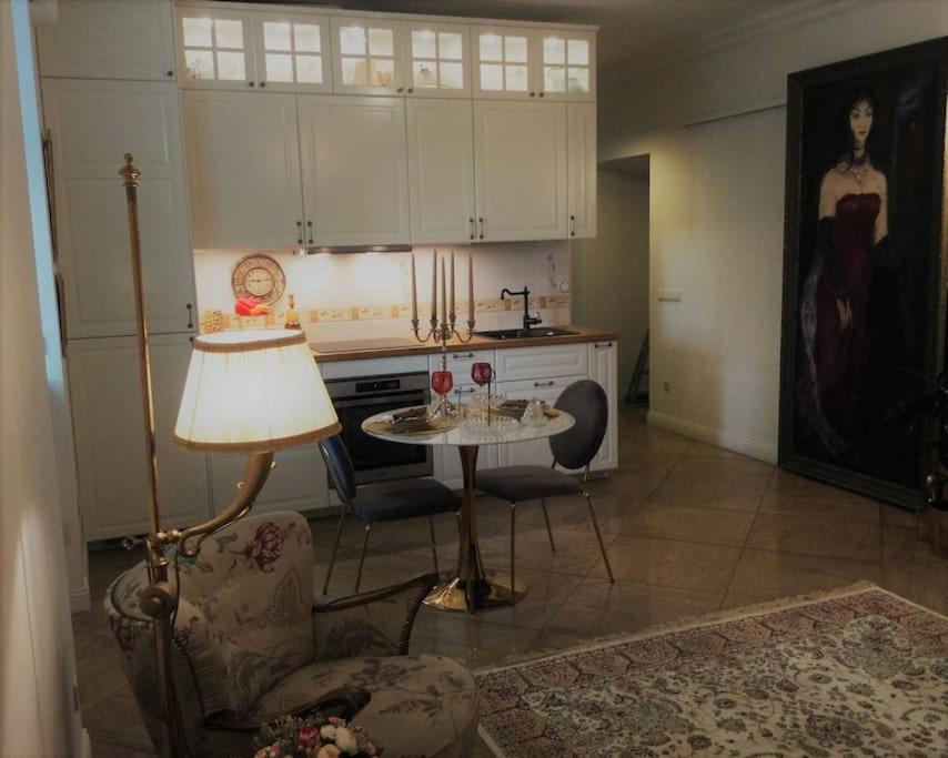 een woonkamer met een tafel met een lamp en een keuken bij Historic house residence in Vilnius
