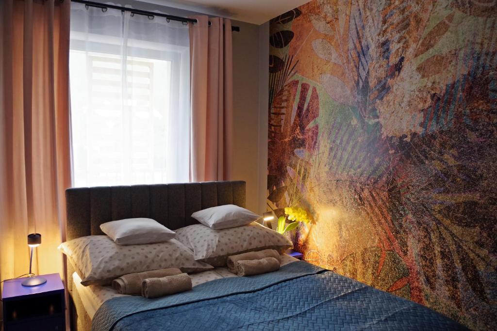 a bedroom with a bed with a large painting on the wall at Apartament Mech & Paprocie in Ustrzyki Dolne