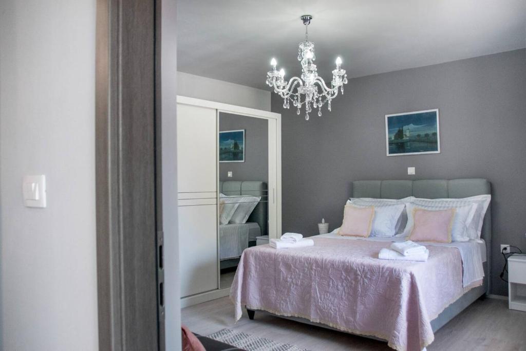 een slaapkamer met een roze bed en een kroonluchter bij Apartment Bruna in Solin