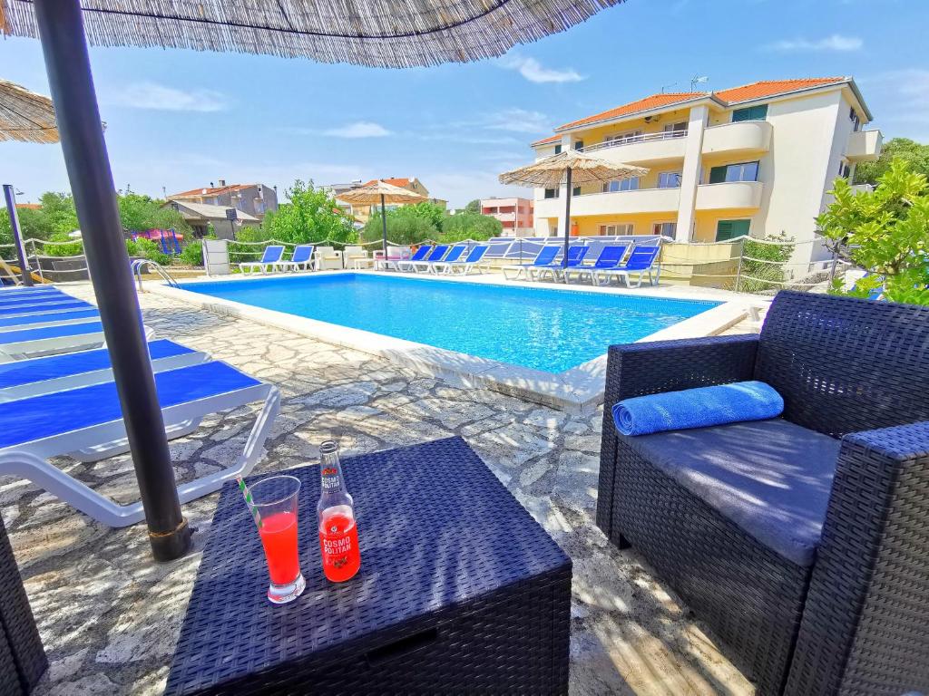 dos bebidas en una mesa junto a una piscina en Apartments CVITA HOLIDAY - Villa NATALI, en Rogoznica