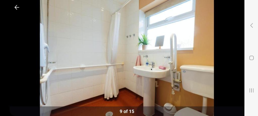 Home in Cheltenham في Golden Valley: حمام مع حوض وحوض استحمام ومرحاض