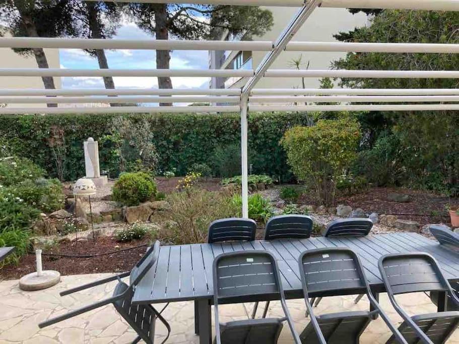 une table de pique-nique et des chaises sous une pergola dans l'établissement Le Papounet Appartement - Maison de 150m2 à 500m de la plage et du centre ville, à Canet