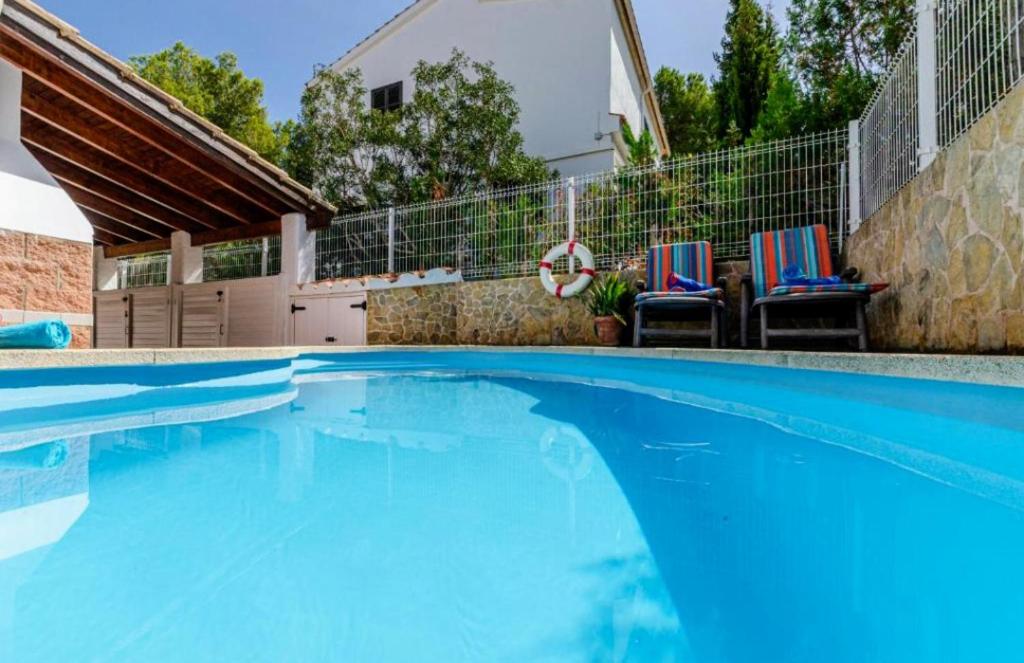- une piscine avec 2 chaises et une maison dans l'établissement SA Calma, à Son Serra de Marina