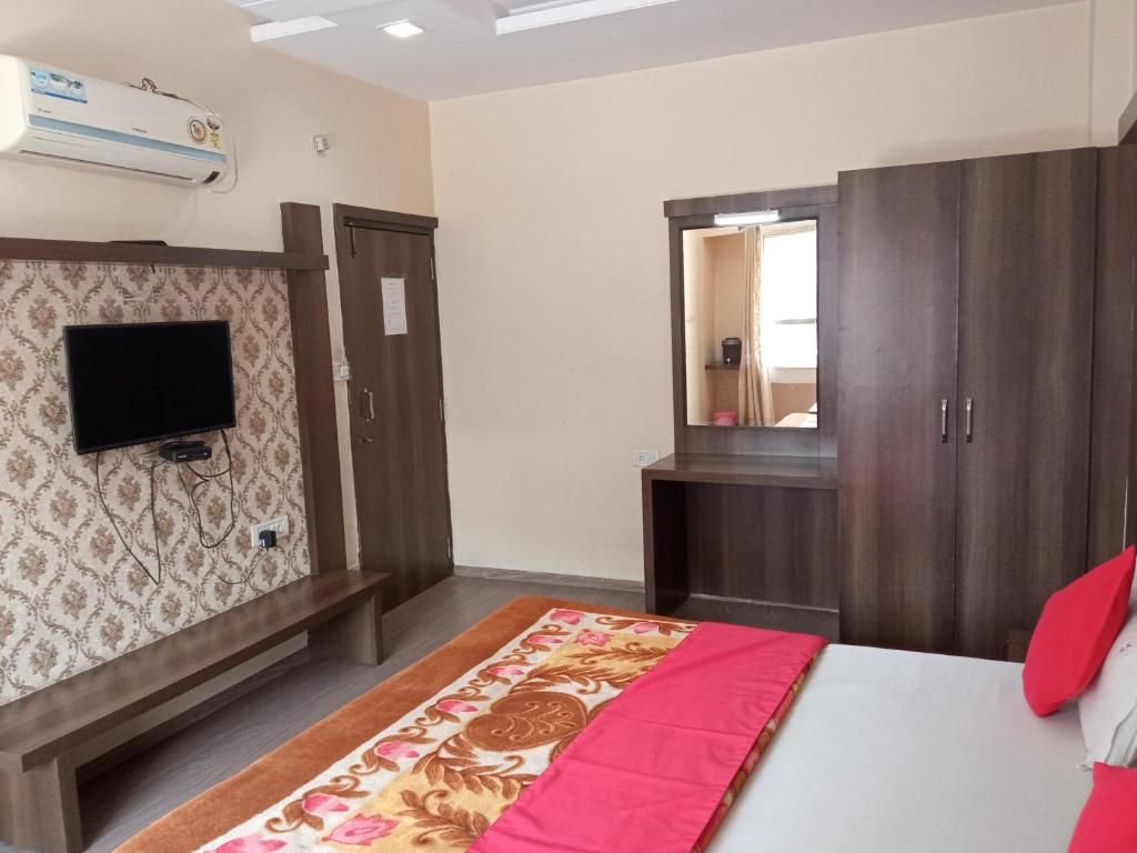 a bedroom with a bed and a mirror and a tv at Pachmarhi Shri Krishna Hotel in Pachmarhī