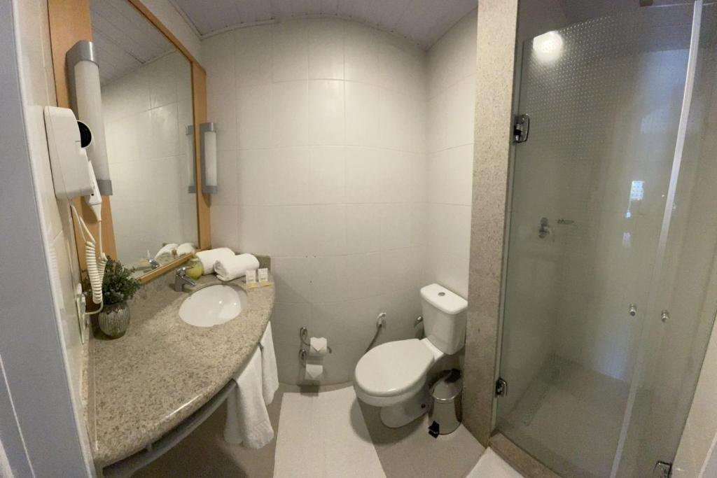 a bathroom with a toilet and a sink and a shower at Hotel Oeste Plaza in Andradina