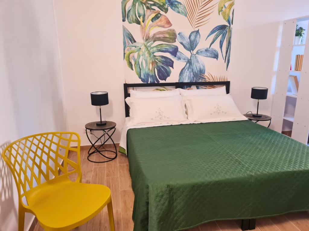 - une chambre avec un lit vert et une chaise jaune dans l'établissement Strada Mastra Casa Vacanze, à Augusta