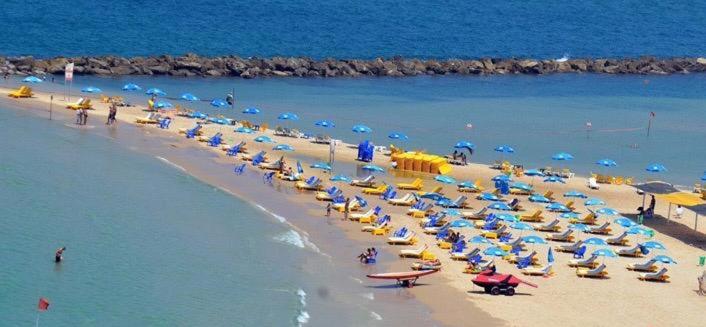 una playa con un montón de sombrillas y gente en ella en Coral guest house Netanya en Netanya