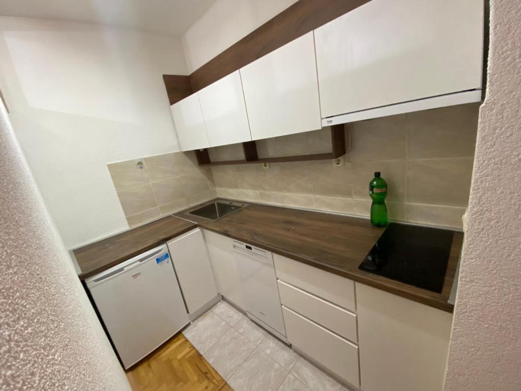 a small kitchen with white cabinets and a green bottle at Lara apartment in Ohrid