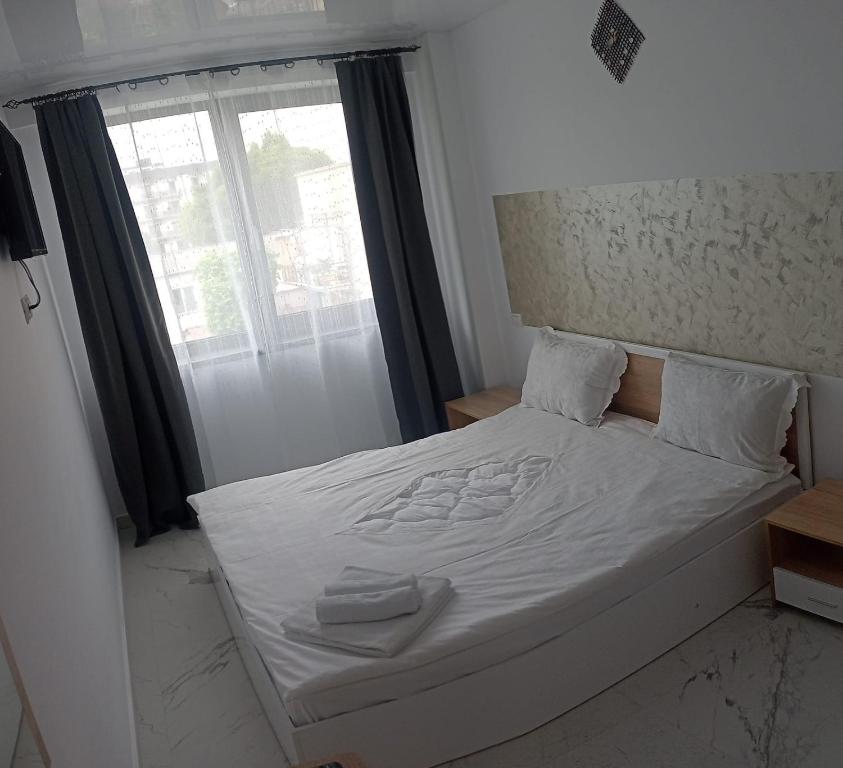 a bedroom with a bed with white sheets and a window at Iris Apartament Eforie Nord in Eforie Nord